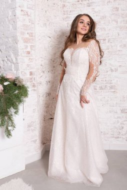 Gelin, beyaz tuğla bir duvarın arka planında, tam gelişim içinde..