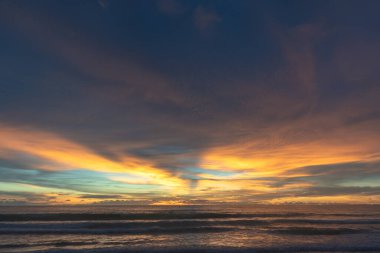 Denizin üzerinde günbatımında gökyüzünde renkli bulutlar renk değiştiriyor.