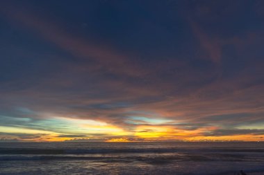 Denizin üzerinde günbatımında gökyüzünde renkli bulutlar renk değiştiriyor.