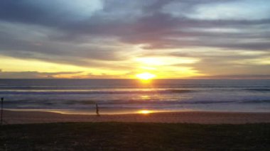 Gün batımında sahilde şaka yapan bir adam.