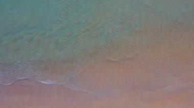 aerial top view sea waves seamless loop on the white sand beach. Wave after wave swept towards the shore. green sea, white bubble waves,and clear sand landscape. Paradise beach.
