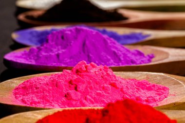 Ahşap kaşıkta pembe toz rengini kapat. Ahşap kaşıkta renkli toz boyası. Siyah arka planda siyah kumaş ve fotokopi alanı. toz boyası insanların kullandığı doğal bir renktir..