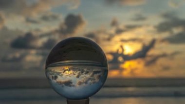 Kristal kürede gün batımını hızlandıran görüntü ters dönmüş gibi görünüyor. Kristal kürelerin içinde gün batımındaki sahilin görüntüsü. Karon plajı Phuket Tayland 'da..