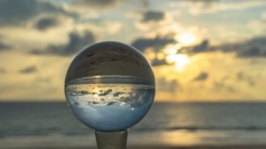 Kristal kürede gün batımını hızlandıran görüntü ters dönmüş gibi görünüyor. Kristal kürelerin içinde gün batımındaki sahilin görüntüsü. Karon plajı Phuket Tayland 'da..
