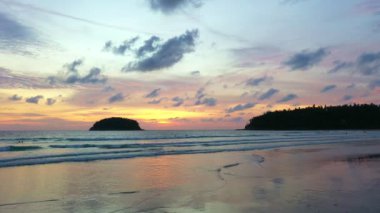 Deniz kenarındaki kayaların üzerinde gün doğumunda inanılmaz bir gökyüzü. Rawai plajı Phuket 'te sarı gün doğumu gökyüzünde bulutlar dolaşıyor. Deniz yüzeyinde gün doğumunun göz kamaştırıcı altın gökyüzü yansıması.  