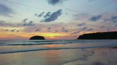 Deniz kenarındaki kayaların üzerinde gün doğumunda inanılmaz bir gökyüzü. Rawai plajı Phuket 'te sarı gün doğumu gökyüzünde bulutlar dolaşıyor. Deniz yüzeyinde gün doğumunun göz kamaştırıcı altın gökyüzü yansıması.  