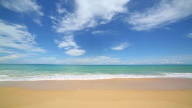 Yeşil deniz dalgaları beyaz uzun sahile vuruyor. Sahilde güzel bir doğa. Mavi arkaplanda beyaz bulut..