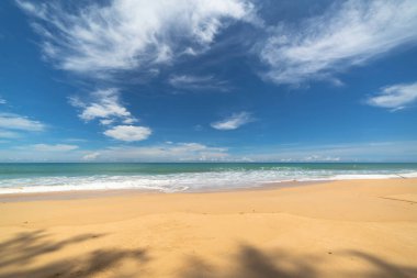 Yeşil denizden gelen pürüzsüz dalgalar beyaz uzun kumsala vurdu.