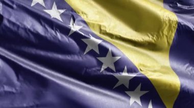 Bosna-Hersek tekstil bayrağı rüzgar döngüsünde yavaşça dalgalanıyor. Bosna-Hersek bayrağı rüzgarda hafifçe sallanıyor. Kumaş dokular. Tam dolgu arkaplanı. 20 saniye döngü. 