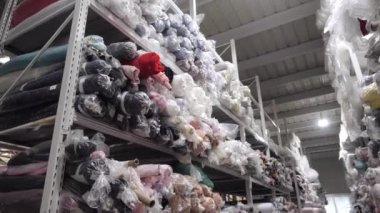 Çoklu renkli kumaş rulolarına sahip bir raf görüntüsü