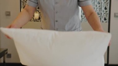 Bir otel çalışanı yatağı hazırlar.