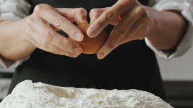 Aşçı yumurtayı kırıyor ve una ekliyor. Yüksek kalite 4k görüntü