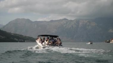 Turistli bir tekne rıhtımdan ayrılıyor. Bir dağ manzarasının arka planında. Yüksek kalite 4k görüntü