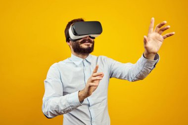 Sanal gerçeklik kaskı takan neşeli genç sakallı adam havaya dokunuyor.