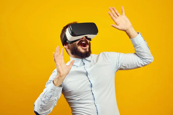 Cheerful young bearded man wearing virtual reality helmet, touching the air — Stock Photo, Image