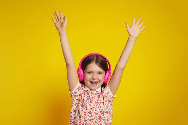 Garota excitada em fones de ouvido sem fio levantando as mãos e gritando sobre amarelo — Fotografia de Stock