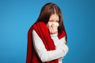 Hasta çocuk beyaz dokuya hapşırıyor, baş harfleri ve burnu akıyor.