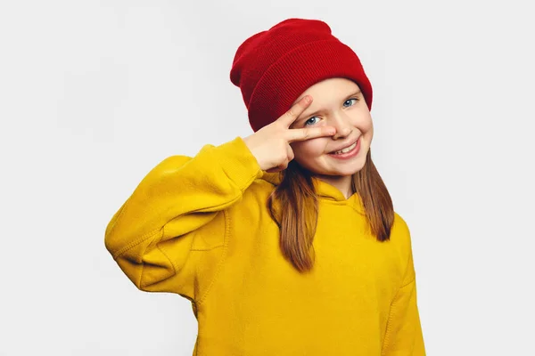 소녀들은 눈 근처에서 승리의 표시나 평화의 표시를 하고 노란 후드와 빨간 모자를 쓰고 있다 — 스톡 사진