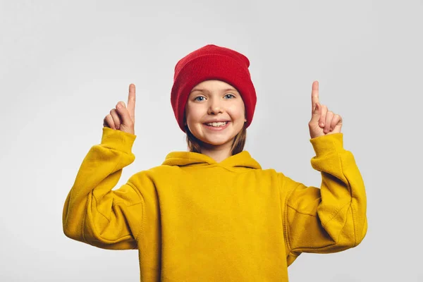 Preciosa niña muestra promo con alegría, puntos por encima con ambos dedos índice — Foto de Stock