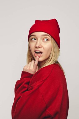 Kız işaret parmağını dudaklarında tutuyor. Bir şey düşünüyor, gizemli bir şekilde yana bakıyor.