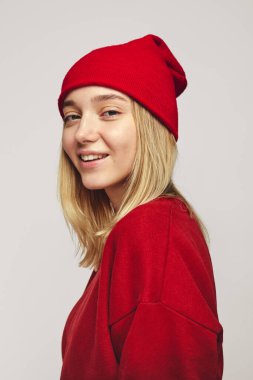 Güzel hippi kız şık kırmızı şapka ve kazak giyiyor, kameraya gülümsüyor.