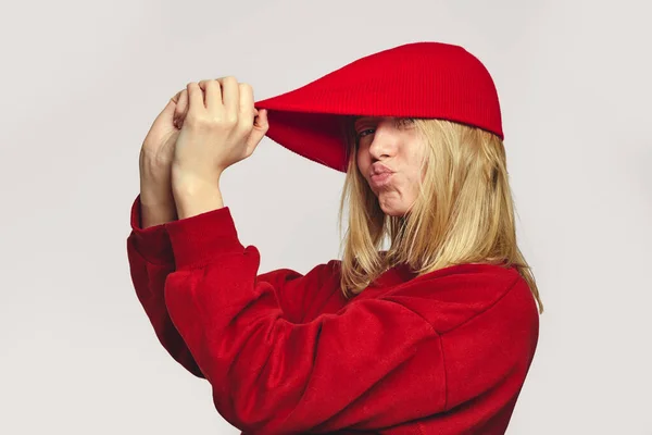 Elegante chica hipster en traje rojo, tire del sombrero exterior, golpe beso en la cámara — Foto de Stock