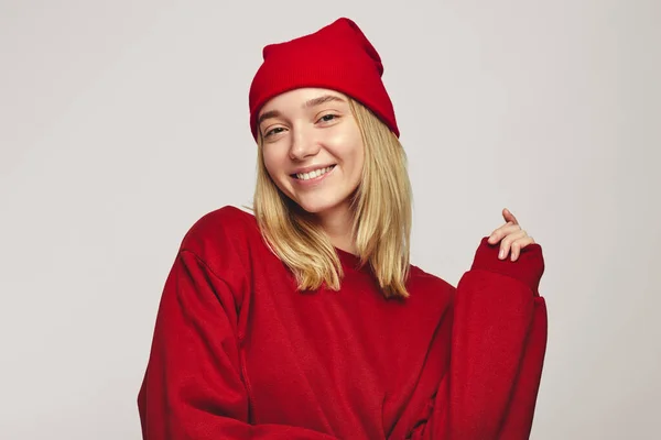멋진 붉은 모자와 운동복을 입고 카메라 앞에서 웃고 있는 멋진 여장 여성 — 스톡 사진