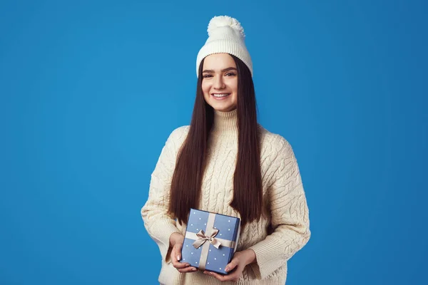 흰색 스웨터를 입고 크리스마스 선물 상자에 싸인 모자를 쓴 귀여운 소녀 — 스톡 사진