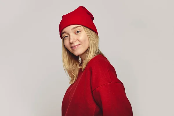 멋진 붉은 모자와 스웨트 셔츠를 입고 카메라 앞에서 웃고 있는 꽤 나멋진 히프 스터 여자 — 스톡 사진