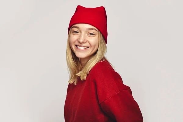 Elegante mujer hipster con elegante sombrero rojo y sudadera, sonriendo a la cámara — Foto de Stock