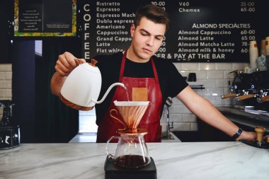 Barista kahve yapıyor, kahve tozunun üzerine sıcak su döküyor.