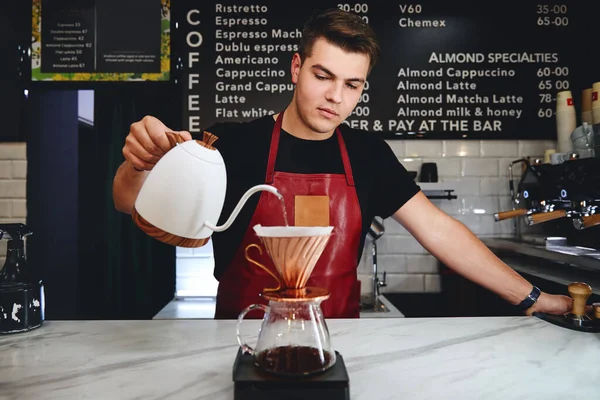Barista kahve yapıyor, kahve tozunun üzerine sıcak su döküyor.