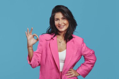 Pembe takım elbiseli neşeli kız mavi arka planda 