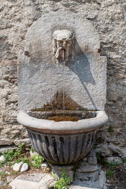 Sakallı bir adamın kafası olan antik taş çeşme.