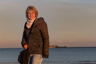 Kışın kumsalda gün batımında bir kadın