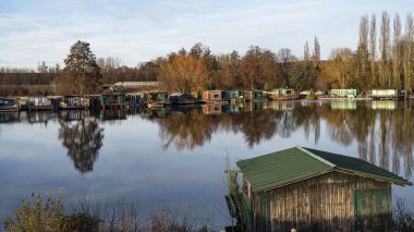 Nehir kıyısında balıkçı kulübeleri ve gölet.