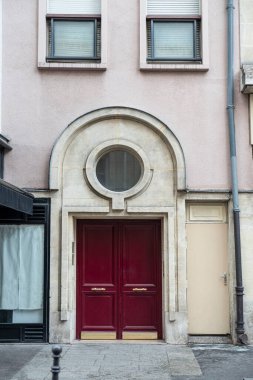 Close-up of a vintage red front door of a building in Paris, with a stone arch above