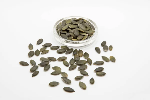 Close up of green and white squash seeds on a white background