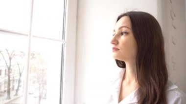 4K Genç bayan pencereden dışarı bakıyor.