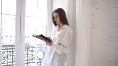 4k businesswoman with notepad, standing near panoramic window