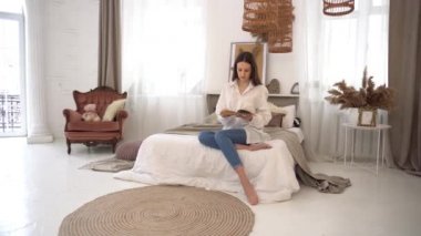 4k Young woman reading book in bed at home.