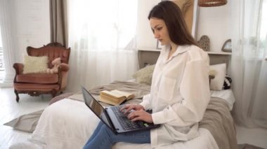 4k Woman in the bedroom is typing on a laptop, distance learning for students