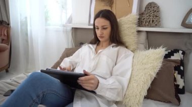 4k Genç kadın yatakta rahatlayan ve dijital tablet bilgisayar kullanan 