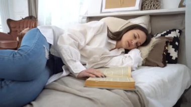 4k Attractive woman sleeping in bed with open book in hands