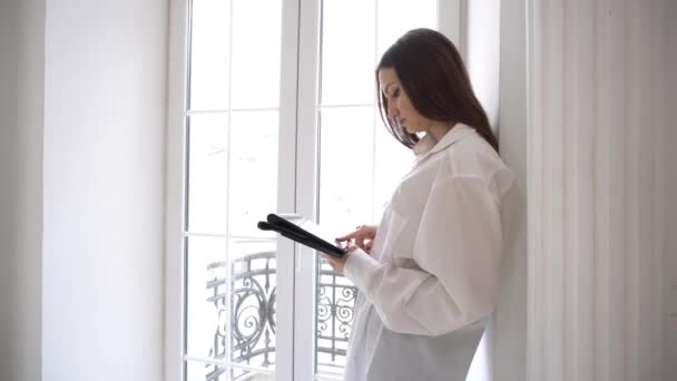 Gemotiveerde Vrouw Houden Moderne Digitale Tablet Buurt Van Het Raam — Stockvideo
