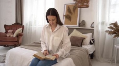 Slow Motion  Attractive woman sitting on bed in the morning reading book