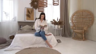 Clever young woman reading the book in bed during vacation