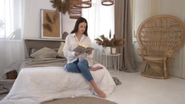 Slow Motion young woman turning the pages of a book while reading in bed