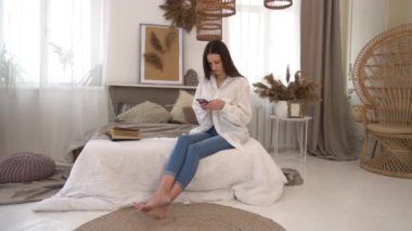Slow Motion Young woman taking a selfie with cell phone on her bedroom bed.