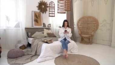 Beautiful young woman using phone, chatting in social network in morning